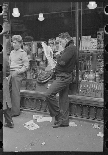 Street scene on 38th Street near 7th Avenue, New York City. Teenager reading newspaper