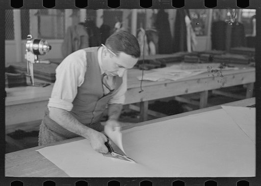 Untitled photo, possibly related to: Louis Gushen, chief cutter in the cooperative garment factory of Jersey Homesteads, is cutting the pattern for a woman's coat. Hightstown, New Jersey