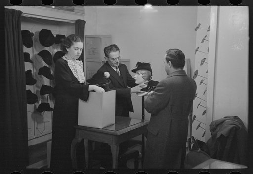 Untitled photo, possibly related to: Model trying on hat for a buyer, New York City showroom, Jersey Homesteads cooperative