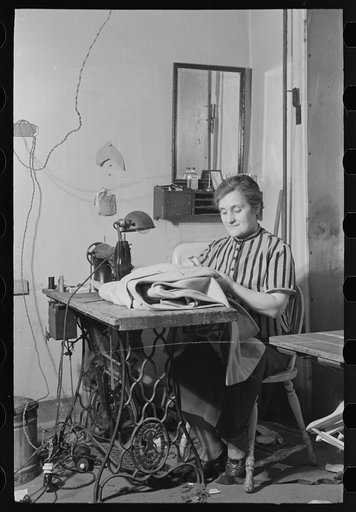 Woman at sewing machine in New York City tailor shop on University Place near 11th Street