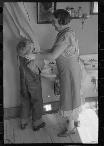 Mrs. Rustan combing her young son's hair. Rustan brothers' farm, Dickens, Iowa. Note running water