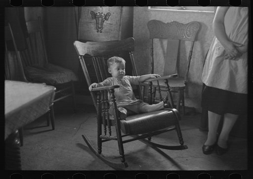 One of L.H. Nissen's children in rocking chair. Nissen shack near Dickens, Iowa. Nissen is a hired man