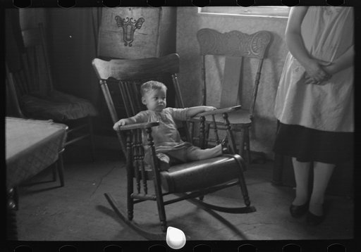 Untitled photo, possibly related to: One of L.H. Nissen's children in rocking chair. Nissen shack near Dickens, Iowa. Nissen is a hired man