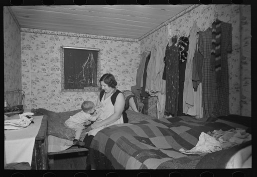 Mother and child in crowded bedroom of home of L.H. Nissen, hired man. He is married, has seven children, one grandchild, all living together in three rooms