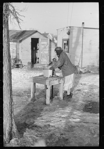 Woman pumping water for laundry, "Shantytown," Spencer, Iowa
