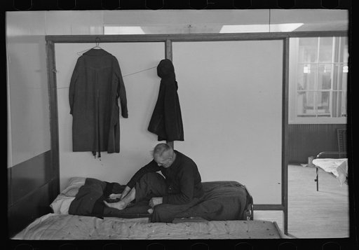 Untitled photo, possibly related to: Man examining ankle, homeless men's bureau, Sioux City, Iowa