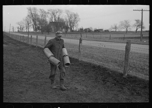Tip Estes carrying tiles to load on a wagon, Fowler, Indiana