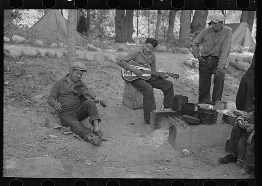 Indian boys playing guitar and violin in blueberry camp near Little Fork, Minnesota
