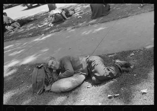 Man resting in park on sack of scratch seed, Minneapolis, Minnesota