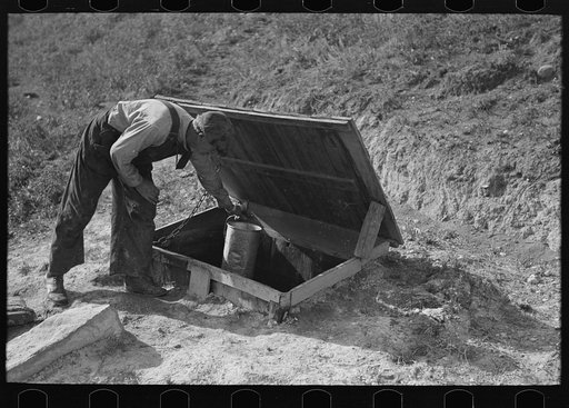 Untitled photo, possibly related to: Herman Gerling dipping water from a spring to fill the barrels on his truck. North Dakota
