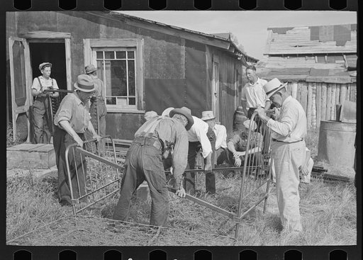 Men taking bed apart at S.W. Sparlin auction sale, Orth, Minnesota