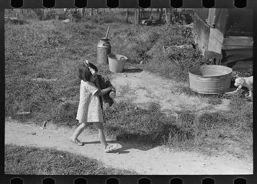Little girl carrying firewood on farm near Northome, Minnesota