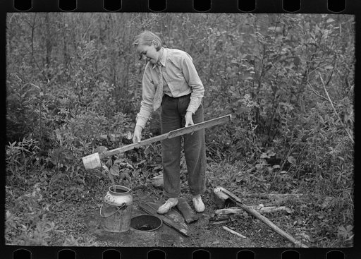 Filling can with water from shallow well on farm near Northome, Minnesota
