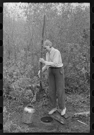 Dipping water from shallow well on farm near Northome, Minnesota