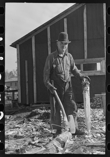 Lumberjack with stake which he has been shaping with broadaxe, at camp near Effie, Minnesta