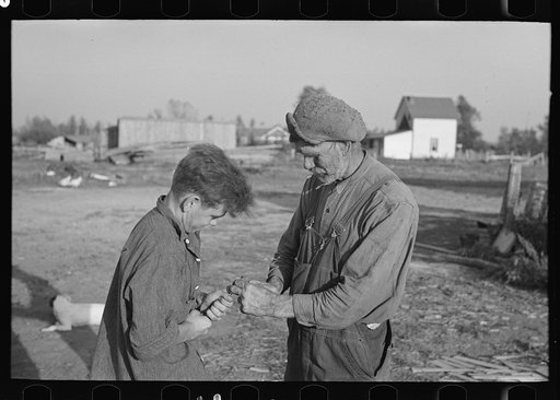 Pioneer farmer and hired man attempting to remove nut from rusted bolt on farm near Northome, Minnesota
