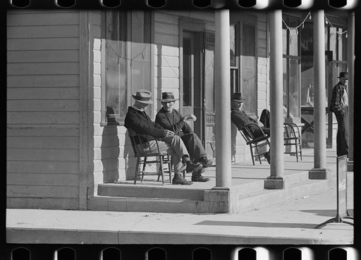 Men sitting in front of hotel in the early morning, Little Fork, Minnesota
