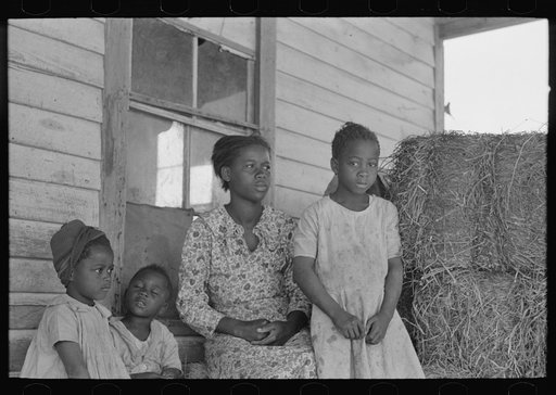 Untitled photo, possibly related to: Part of sharecropper family on porch of cabin. Note the absence of storage space