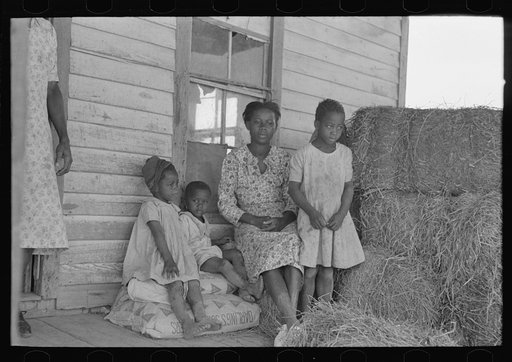 Part of sharecropper family on porch of cabin. Note the absence of storage space