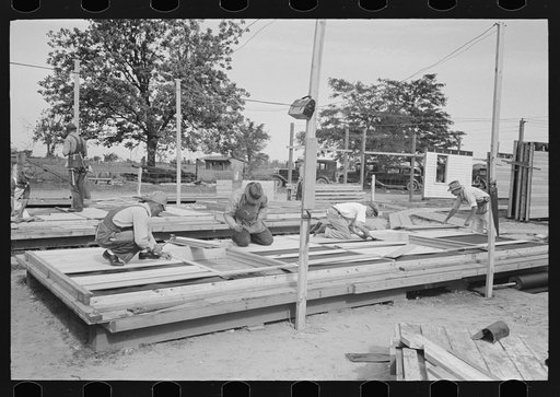 Untitled photo, possibly related to: House plant. Putting pre-cut siding on the wall panels. Note templates to adjust the siding of the ends and in the middle. Southeast Missouri Farms Project