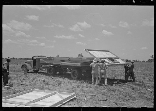 Barn erection. Unloading barn panels around circumference of the foundation. These panels were loaded in order of distribution at the site. Southeast Missouri Farms Project
