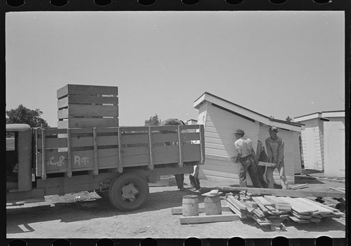 Untitled photo, possibly related to: Barn erection. Unloading barn panels around circumference of the foundation. These panels were loaded in order of distribution at the site. Southeast Missouri Farms Project