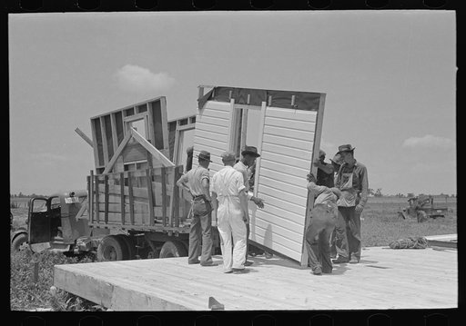 House erection. Unloading panels onto the platform. Southeast Missouri Farms Project