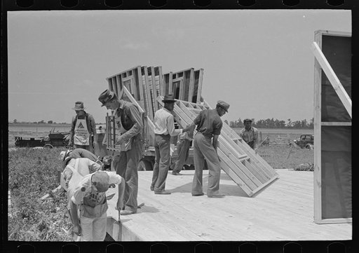 House erection. Unloading panels onto the platform. Note that subfloor is just being finished. Southeast Missouri Farms Project