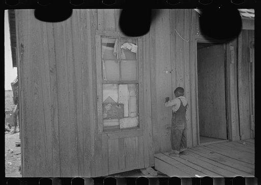 Untitled photo, possibly related to: Child of former sharecropper, playing primitive musical instrument made by stretching wire from one nail to another creating sort of violin. Southeast Missouri Farms