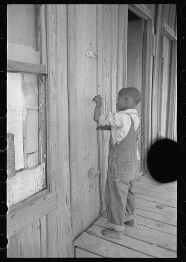Untitled photo, possibly related to: Child of former sharecropper, playing primitive musical instrument made by stretching wire from one nail to another creating sort of violin. Southeast Missouri Farms