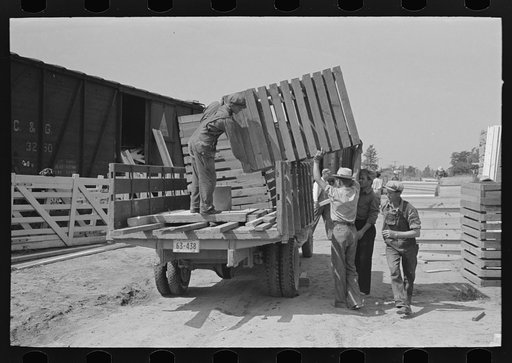 Untitled photo, possibly related to: Southeast Missouri Farms Project. Transportation; privies being loaded onto truck. Wood cribbing is for privy well