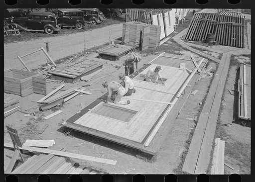 House plant. Fitting windows and siding to the wall panels. Note framing tables and stacks of window and door inserts at the left. Southeast Missouri Farms Project