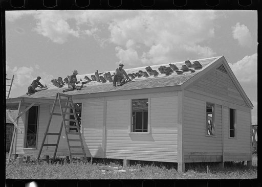 Untitled photo, possibly related to: Southeast Missouri Farms Project. House erection. Shingling crew at work on roof. Shingles are tucked in roof lath to keep them from blowing away