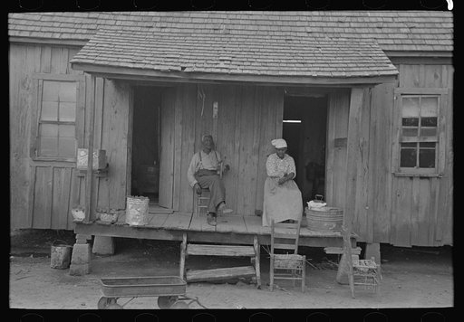Old Negro couple sitting on front porch of shack home, Southeast Missouri Farms