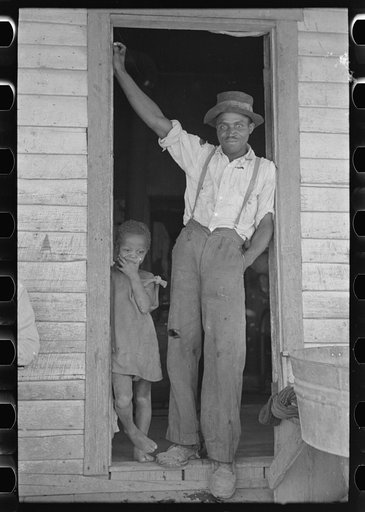Sharecropper and young daughter standing in doorway of shack home. New Madrid County, Missouri