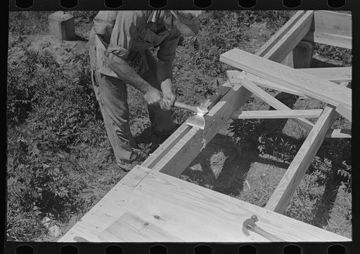 Southeast Missouri Farms Project. House erection. Axeing crown of joist. Southeast Missouri Farms project field
