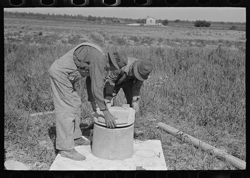 Untitled photo, possibly related to: Southeast Missouri Farms Project. Fitting vent stack and seat cover to sanitary base of privy
