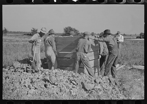 Southeast Missouri Farms Project. Privy erection. Placing wood cribbing in privy well