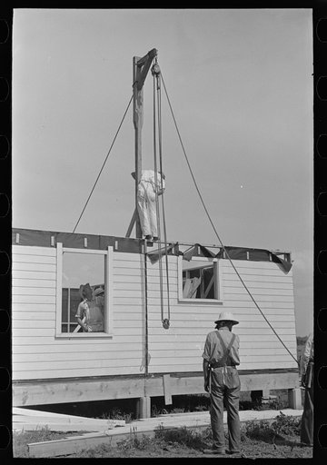 Southeast Missouri Farms Project. House erection. Gin pole is raised and braced for the erection of gable end