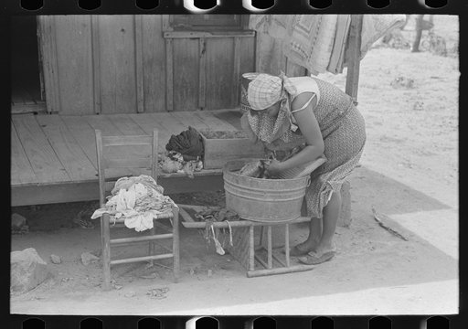 Wife of FSA (Farm Security Administration) client, former sharecropper, washing clothes in front of old cabin, Southeast Missouri Farms