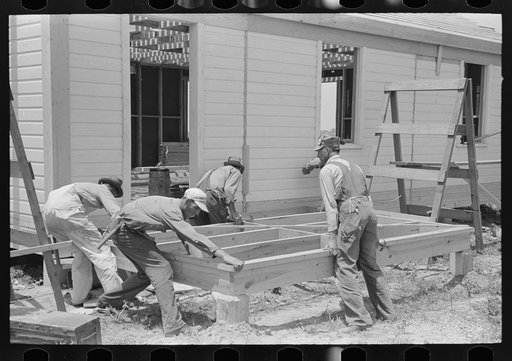 Southeast Missouri Farms Project. House erection. Porch floor being shoved into place. Note five-man crew