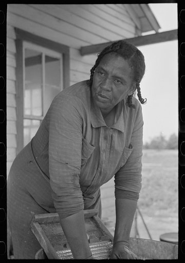 Wife of FSA (Farm Security Administration) client, former sharecropper, washing on back porch of old home, Southeast Missouri Farms