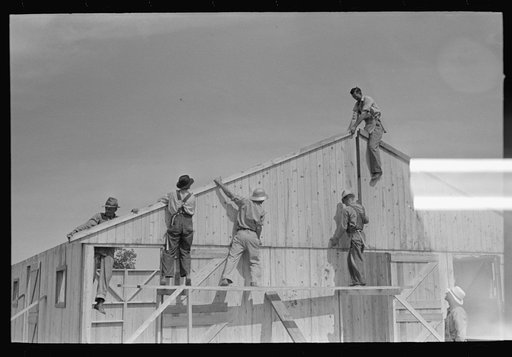 Barn erection. Sliding last half of one gable end into place. Note that gable end sheathing overlaps sheathing of wall panels, forming a drip. Southeast Missouri Farms Project