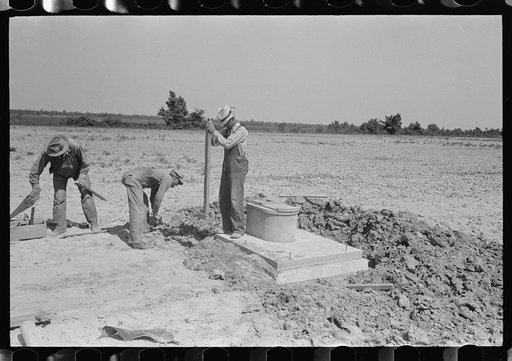 Southeast Missouri Farms Project. Privy erection. Back filling and tamping the earth around sanitary base and mud sill