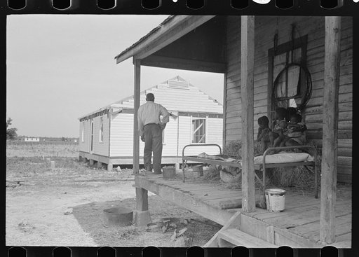 FSA (Farm Security Administration) client and family, former sharecroppers, looking at new home from porch of old shack, Southeast Missouri Farms