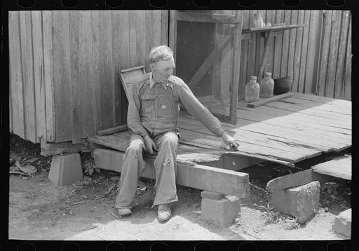 Farmer sitting on rotted porch of his old home, Southeast Missouri farms