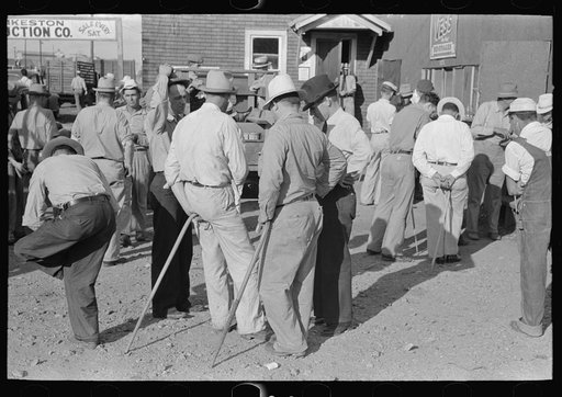 Group of farmers at auction with auction assistants resting on canes used for guiding livestock, Sikeston, Missouri