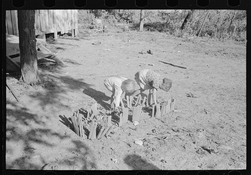 Children of sharecropper, cut-over farmer, tending garden in front of home, New Madrid County, Missouri