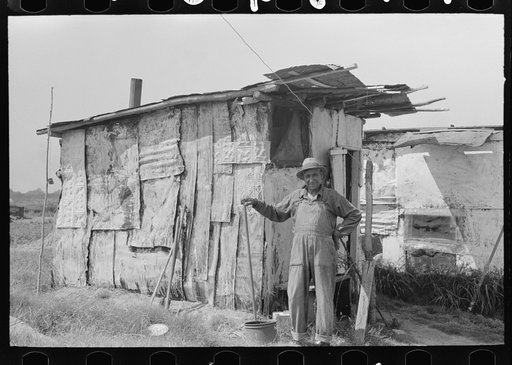 Resident of "Tin Town" on river side of levee, Caruthersville, Missouri, in front of one of his two shacks