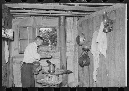 Squatter makes coffee in kitchen at his home in abandoned warehouse, Caruthersville, Missouri